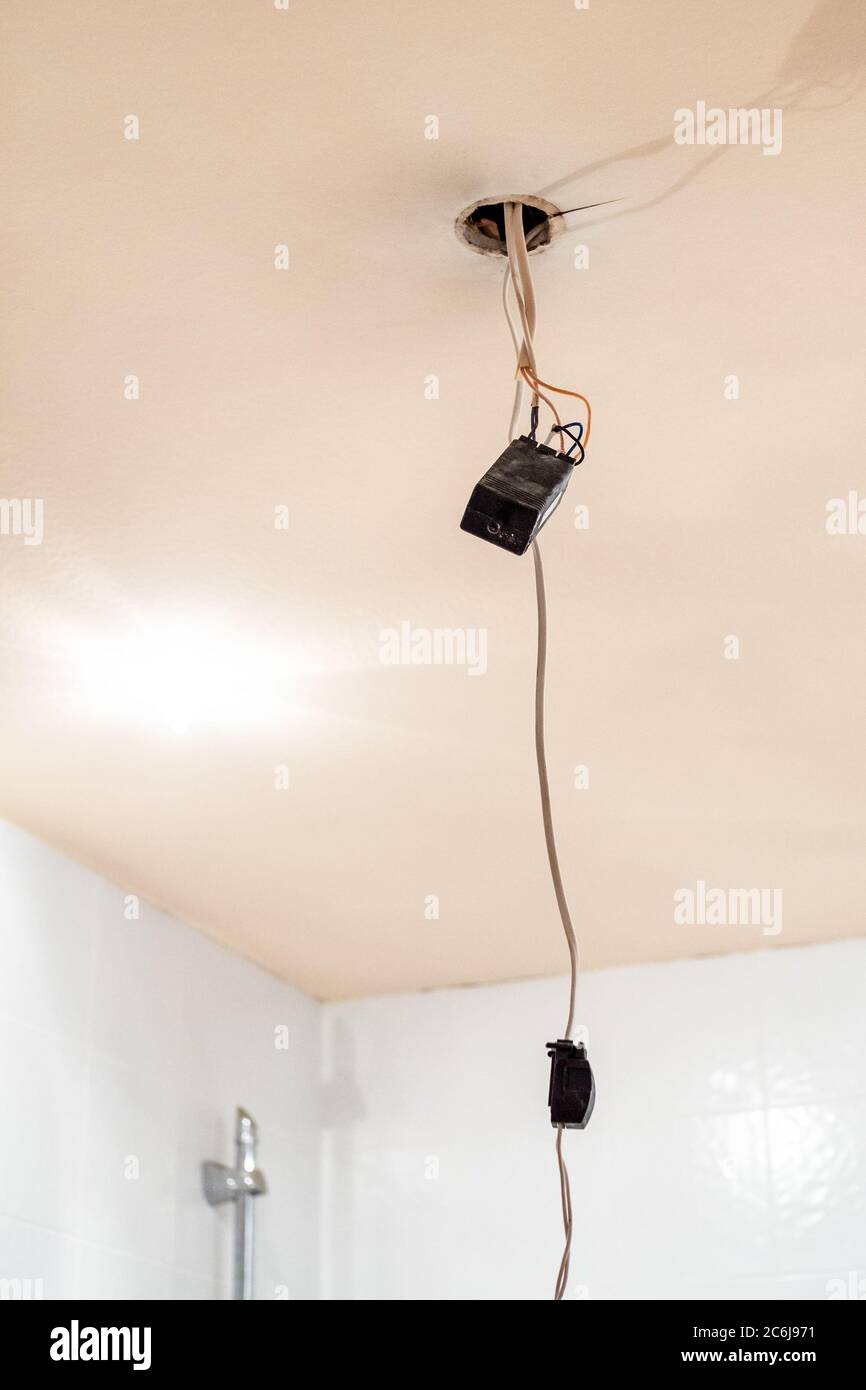 Alter elektronischer Transformator für Halogenlampen, die an elektrischen Drähten von der abgehängten Decke aus Gipskarton hängen Stockfoto