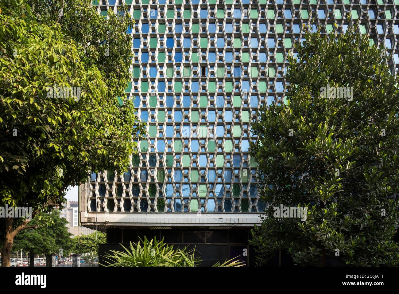 Teilweise verdeckt von Bäumen, horizontale axiale Ansicht der Westhöhe mit särgigen Betonplatten. Universität für Medizin (Rangun College of Stockfoto