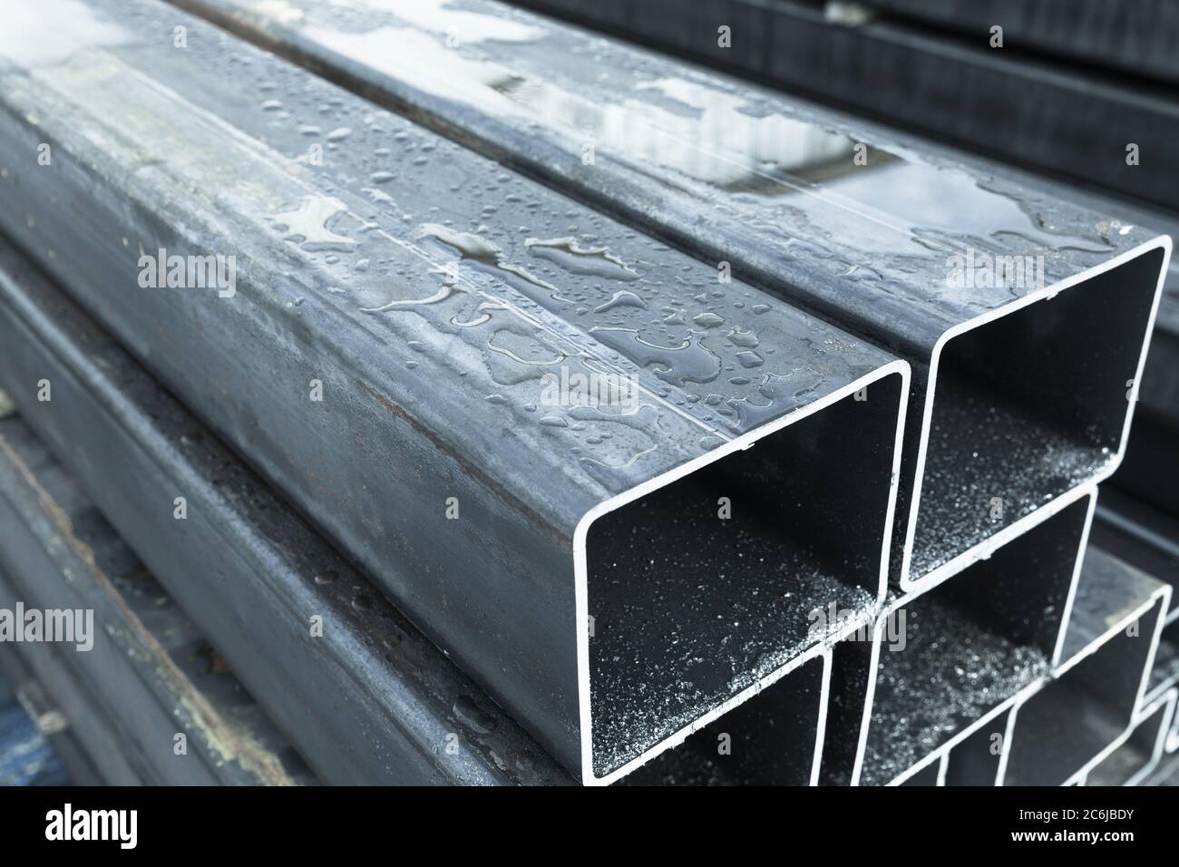 Stapel von gewalzten Metallprodukten, nassen Stahlrohren mit rechteckigem Querschnitt, Nahaufnahme mit selektivem Fokus Stockfoto