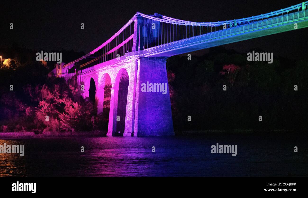 Bangor, Gwynedd, N Wales. Die Menai-Hängebrücke über die Menai-Straße wird in Regenbogenfarben beleuchtet, um 72 Jahre NHS zu feiern Stockfoto