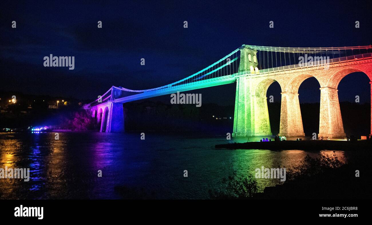 Bangor, Gwynedd, N Wales. Die Menai-Hängebrücke über die Menai-Straße wird in Regenbogenfarben beleuchtet, um 72 Jahre NHS zu feiern Stockfoto