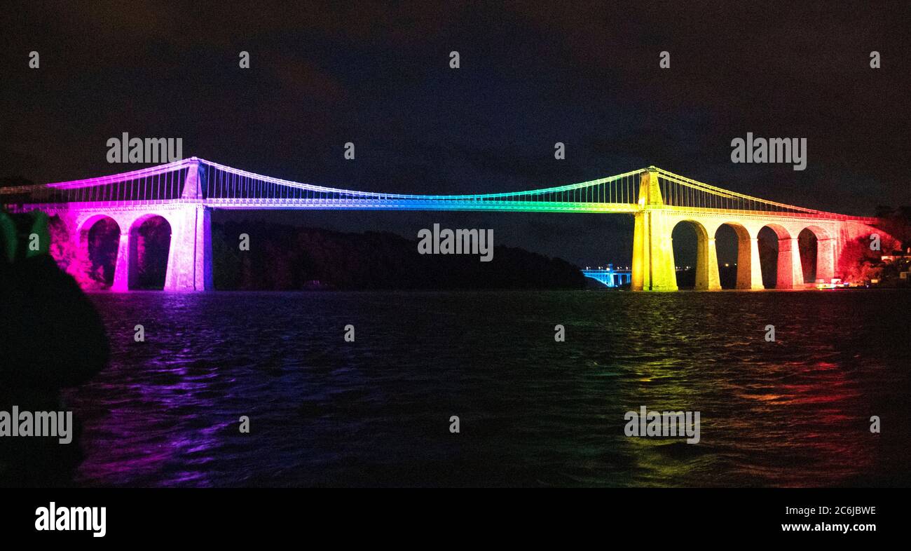 Bangor, Gwynedd, N Wales. Die Menai-Hängebrücke über die Menai-Straße wird in Regenbogenfarben beleuchtet, um 72 Jahre NHS zu feiern Stockfoto