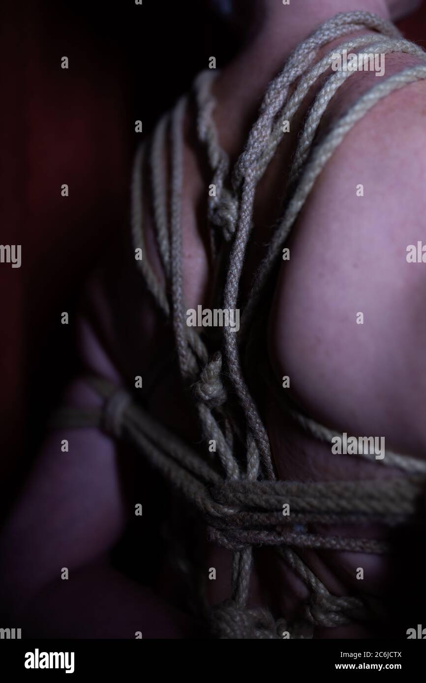 Anonyme Low-Key-ältere Dame in Shibari TK und Karada mit Hanfseil gebunden - Rückansicht Stockfoto