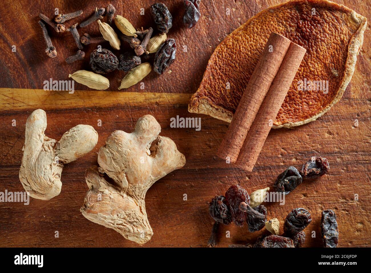 Eine Mischung aus trockenen Mulling Gewürze (Ingwer, Orangenschale, Rosinen, Nelken, Zimtstange, Kardamom-Schoten) auf Holzbrett. Stockfoto