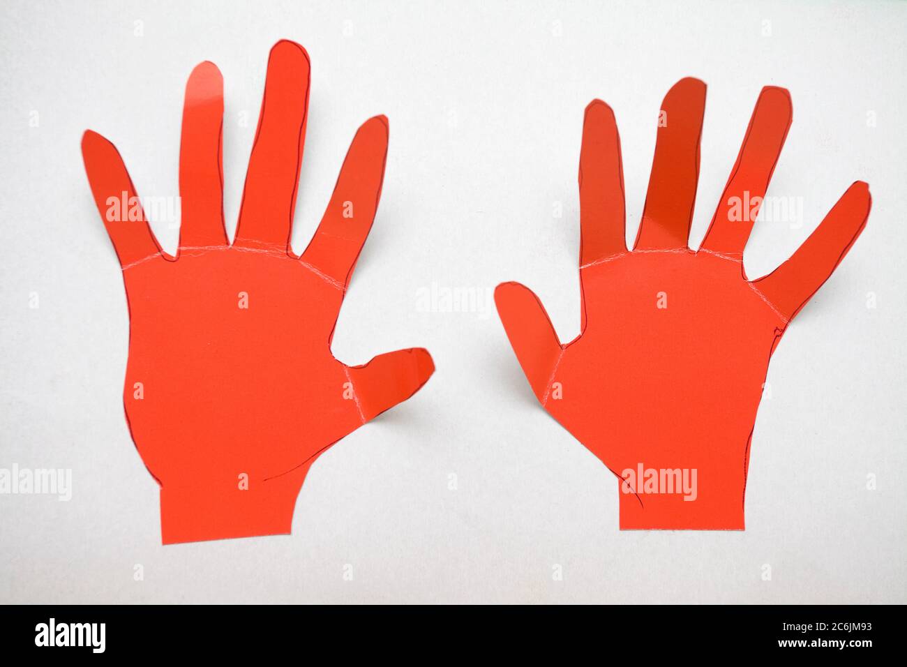 Rote Pappe schneiden Hände auf weißem Kartenhintergrund Stockfoto