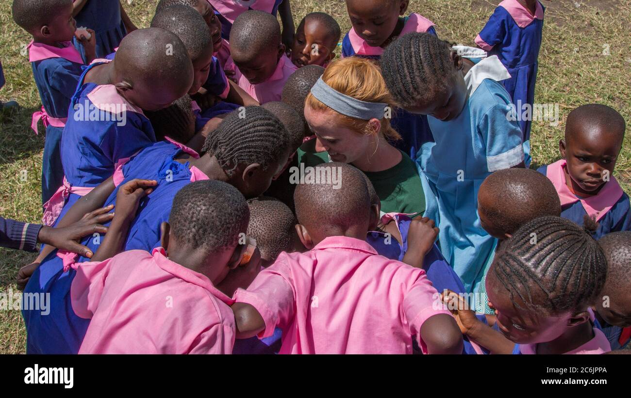 Eine Gruppe von Schulkindern versammelt sich um einen jungen Mitarbeiter der Southern Baptist Missions in ihrer Schule in der Nähe von Ahero, Kenia Stockfoto