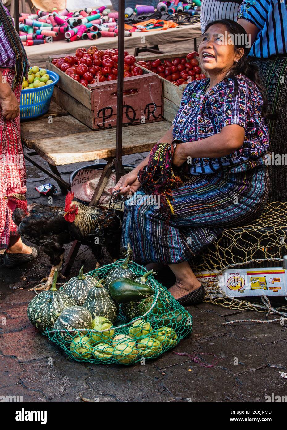 Guatemala, Solola Department, Santiago Atitlan, EINE Maya-Frau in traditioneller Kleidung sitzt mit ihren Hühnern und produziert auf dem wöchentlichen offenen Markt. Stockfoto