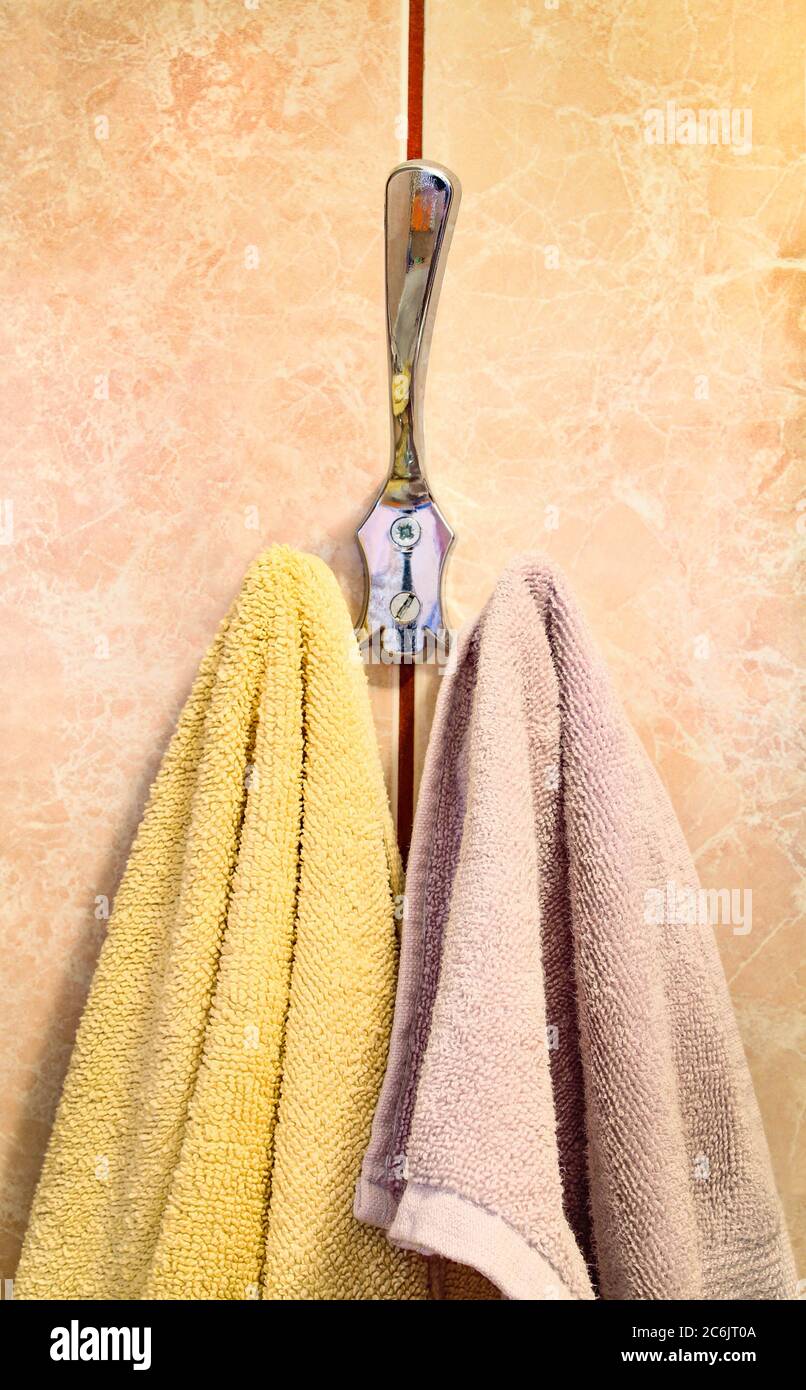 Zwei Baumwollhandtücher, die am Badezimmerhaken hängen. Nahaufnahme Stockfoto