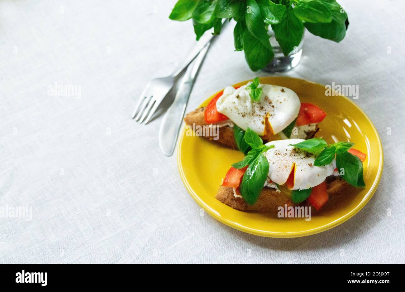 Leckere Sandwiches mit Basilikum, Tomaten und pochierten Eiern auf dem Teller. Platz kopieren Stockfoto