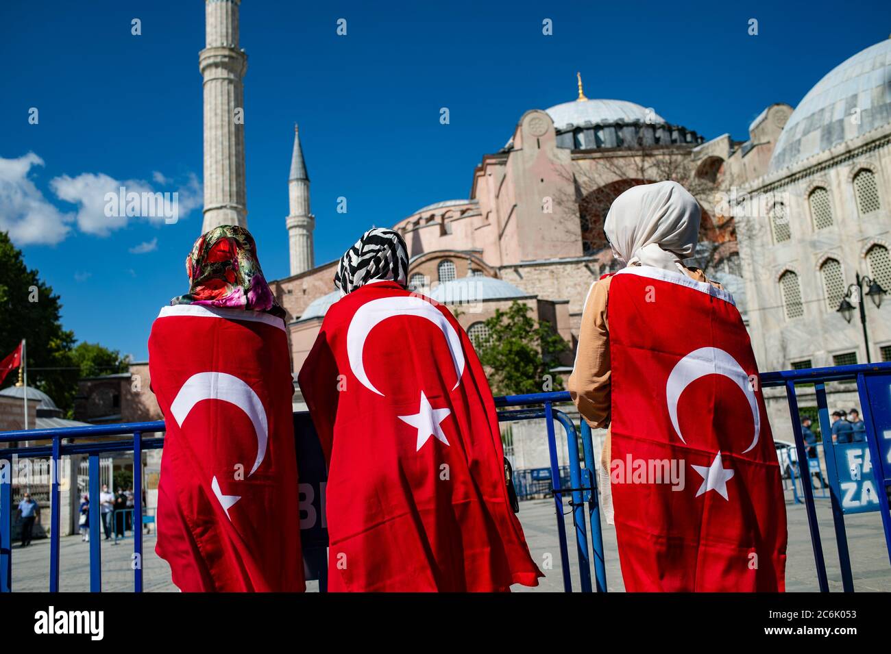 Istanbul, Türkei. Juli 2020. Menschen stehen vor der Hagia Sophia, eingewickelt in türkische Nationalflaggen. Nach der Gerichtsentscheidung über die Hagia Sophia hat der türkische Präsident Erdogan die Eröffnung des Gebäudes für das islamische Gebet angeordnet. Zuvor hatte das Oberverwaltungsgericht den Status der ehemaligen Kirche als Museum aufgehoben und damit den Weg für die Umwandlung in eine Moschee frei gemacht. Quelle: Yasin Akgul/dpa/Alamy Live News Stockfoto