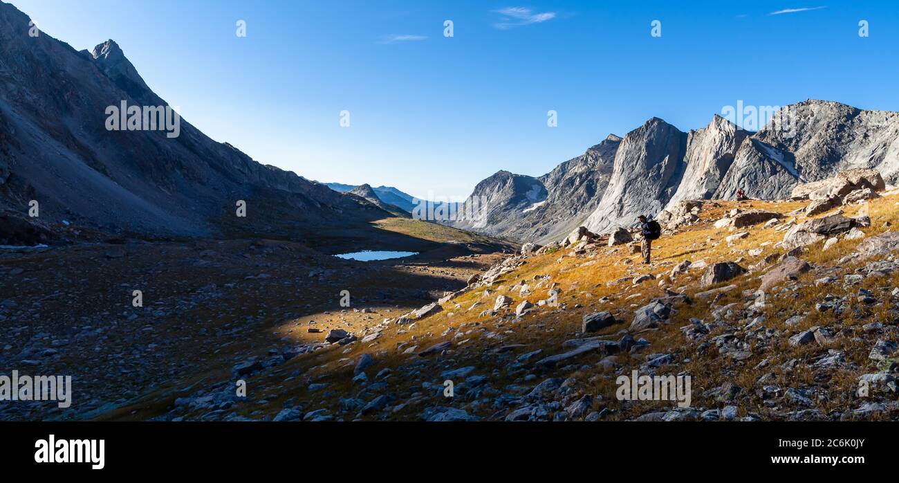 Ein Backpacker hält beim Aufstieg zum RAID/Bonneville Pass inne, um die Sonne über den Gipfeln im Osten zu sehen. Wind River Range, Wyoming. Stockfoto