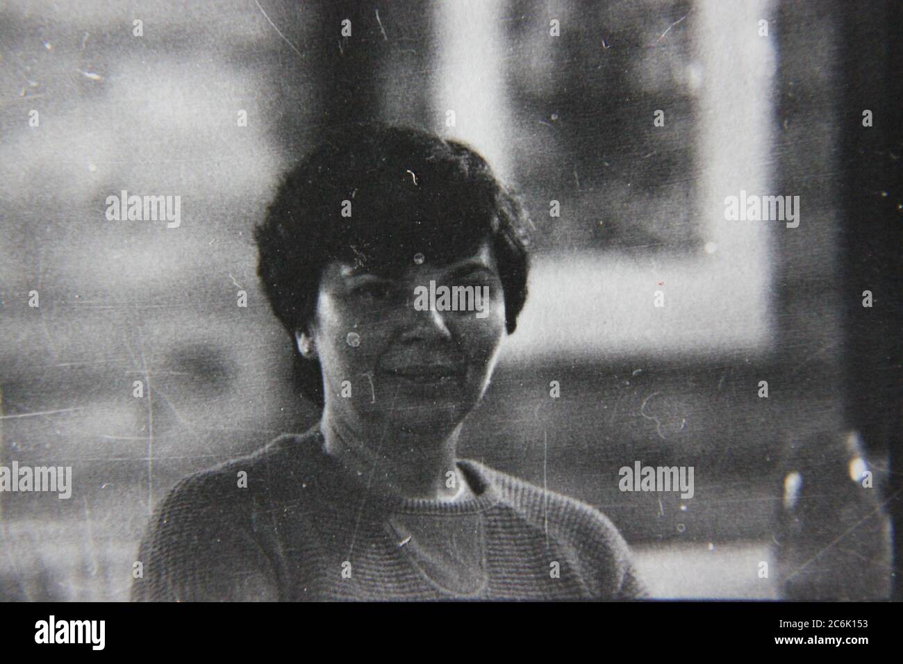 Schönes Schwarz-Weiß-Foto aus den 1970er Jahren von einer Frau mittleren Alters, die glücklich die Zeit herumsitzt. Stockfoto