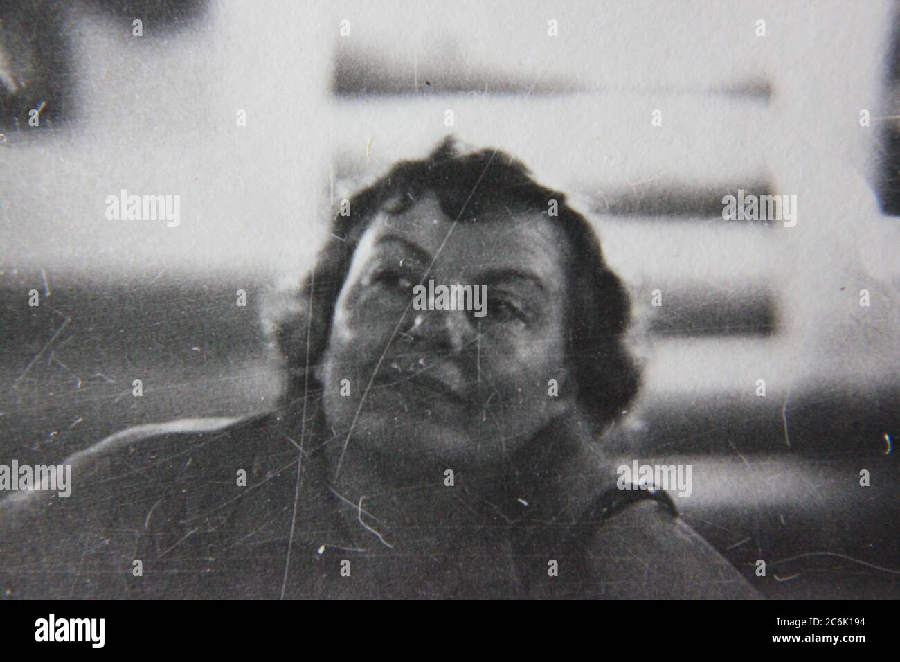 Schönes Schwarz-Weiß-Foto aus den 1970er Jahren von einer Frau mittleren Alters, die glücklich die Zeit herumsitzt. Stockfoto