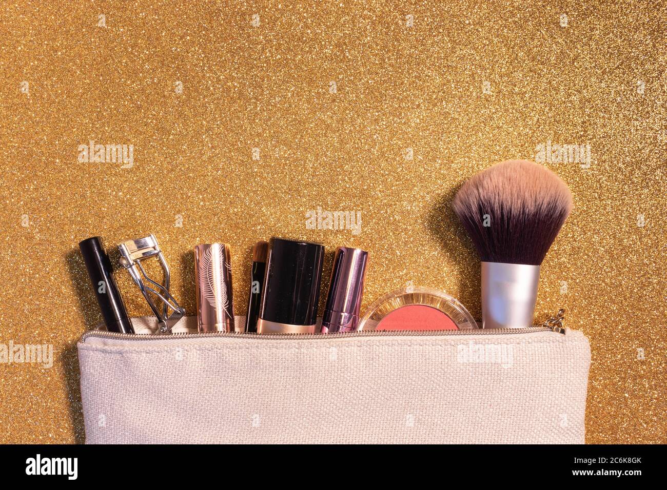 Make-up-Koffer mit Pinsel, Lippenstifte, Fundament und Werkzeuge, Gold Glitter Hintergrund Stockfoto