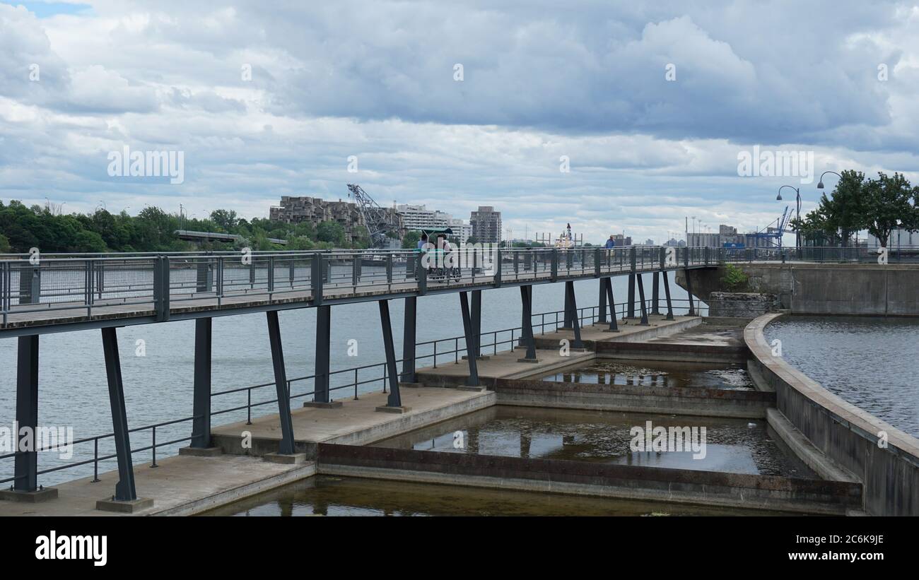 Montreal, QC/ Kanada - 25. Juni 2020: Eine Familie fährt mit einem Vierrad über eine Brücke am alten Hafen, nachdem die Coronaviren leicht gesperrt wurden. Hintergrund Stockfoto