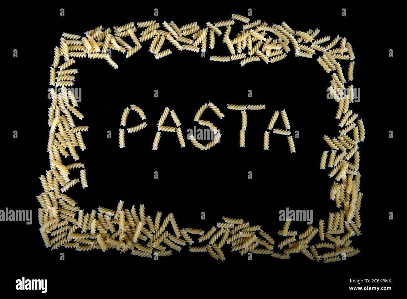 Das Wort Pasta mit Pasta-Schrauben in einem Rahmen von Nudeln Spiralen geschrieben. Schwarzer Hintergrund. Stockfoto
