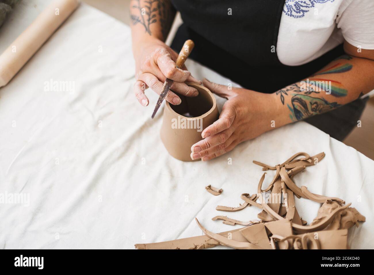 Nahaufnahme Frau Hände mit bunten Tattoo Arbeit mit Ton und die Schaffung von Keramik-Objekt in Töpferei Studio. Stockfoto