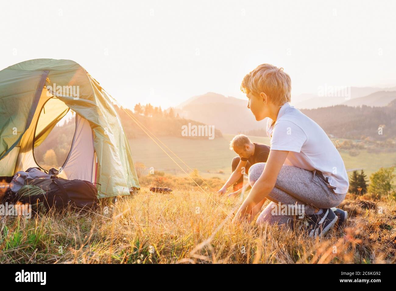 Vater und Sohn setzen am Abend im Tal des Sonnenuntergangs ein Zelt auf Stockfoto
