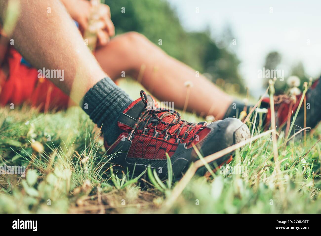 Trekkingschuhe für Rucksacktouristen aus nächster Nähe. Mann hat eine Pause auf grünem Gras sitzen und genießen Bergwandern, aktiv Sport Rucksackwandern Gesundheit Stockfoto