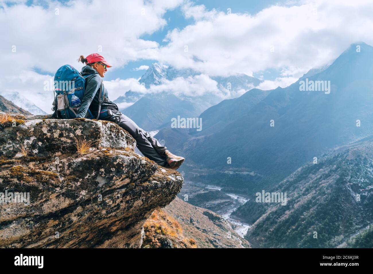 Junge Wandererin Backpacker weiblich sitzt am Klippenrand und genießt das Imja Khola Tal während der Höhenwanderung des Everest Base Camp (EBC) Route nea Stockfoto