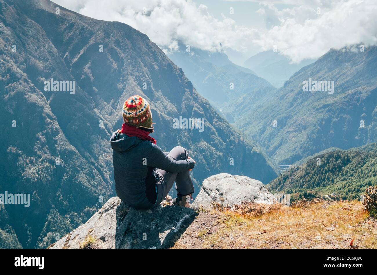 Junger Wanderer Backpacker sitzt am Gipfelrand und genießt Bergblick Tal während der Höhenlage Everest Base Camp (EBC) Trekking-Route in der Nähe von Ph Stockfoto