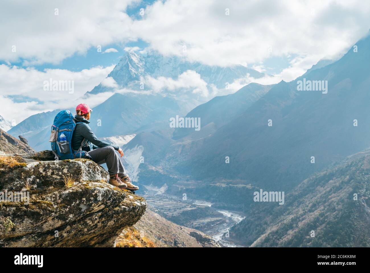 Junge Wandererin Backpacker weiblich sitzt am Klippenrand und genießt Ama Dablam 6,812m Gipfelblick während Everest Base Camp (EBC) Trekking Route in der Nähe von Ph Stockfoto