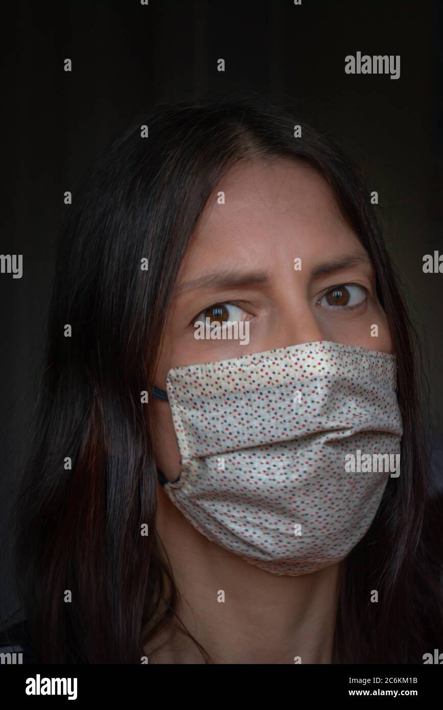 Frau mit dunklem Teint und dunklen Augen trägt eine schützende Stoff Gesichtsmaske während der 2020 globalen Covid 19 / Coronavirus-Krankheit Pandemie, Bild in England, Großbritannien aufgenommen Stockfoto