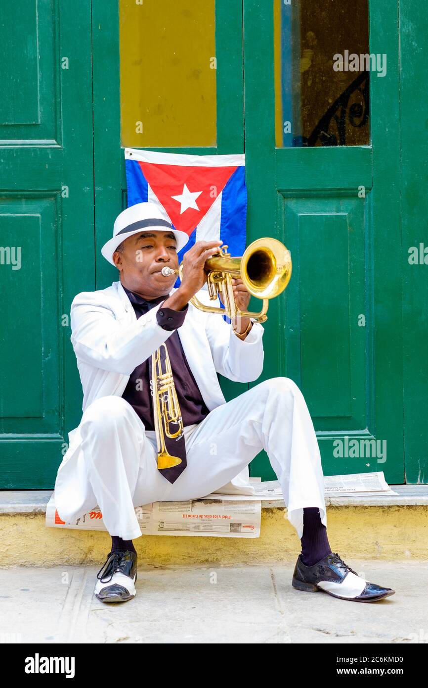 Kubanischer Musiker, der neben einer kubanischen Flagge in Havanna Trompete spielt Stockfoto