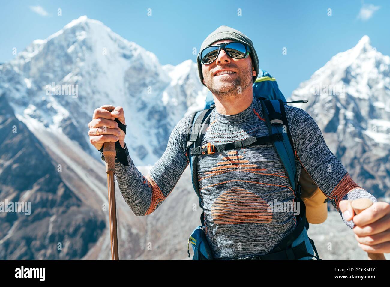 Portrait des lächelnden Wanderers auf Taboche 6495m und Cholatse 6440m Gipfel Hintergrund mit Trekkingstöcken, UV-schützende Sonnenbrille. Er genießt den Berg Stockfoto