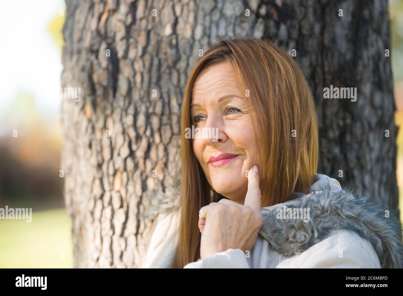 Portrait Attraktive reife Frau in warmen Jacke im Freien, posiert glücklich entspannt, nachdenklich, verschwommen Hintergrund. Stockfoto