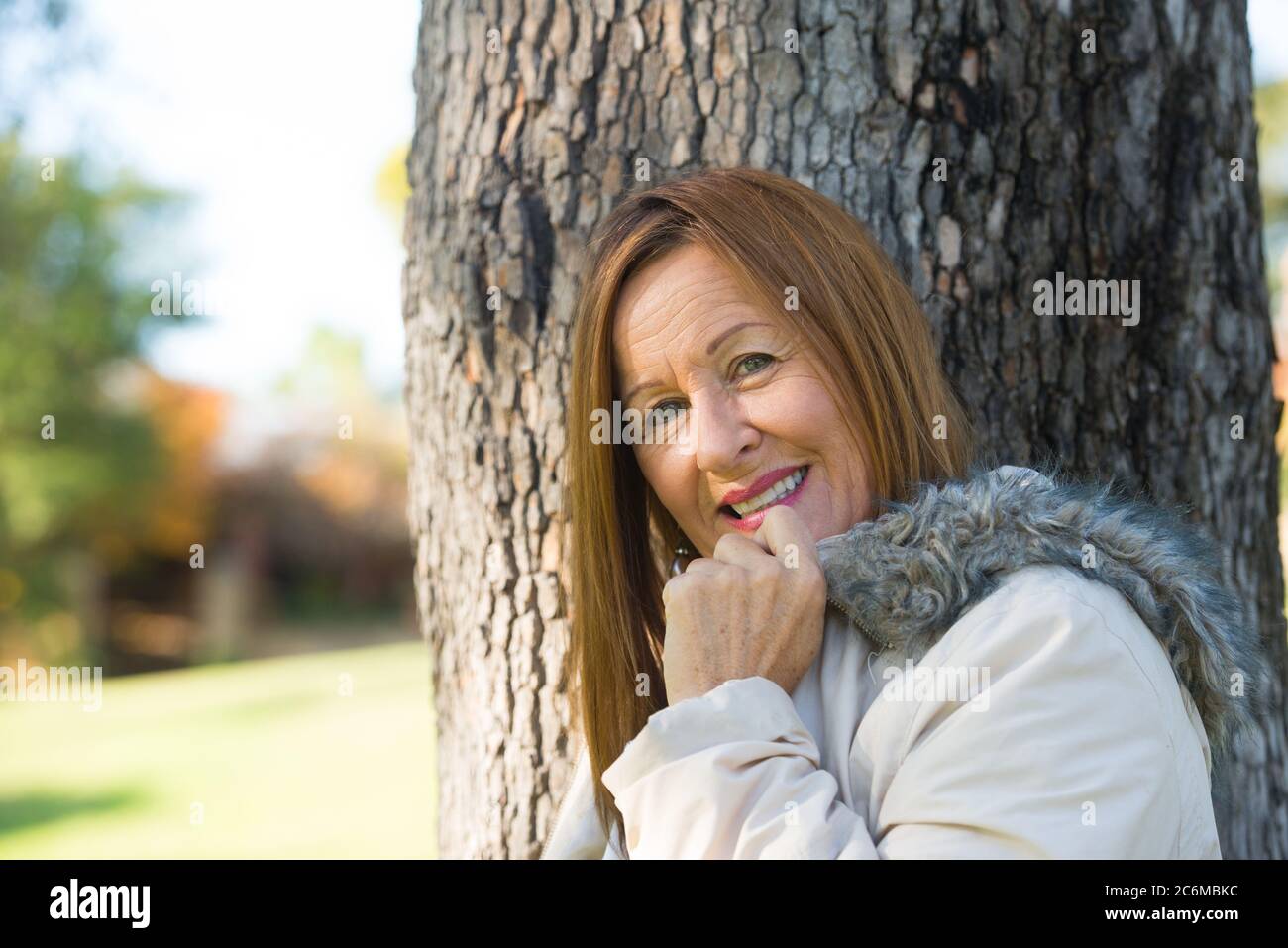 Portrait Attraktive reife Frau in warmen Jacke im Freien, posiert glücklich entspannt, freundlich und zuversichtlich, verschwommener Hintergrund. Stockfoto