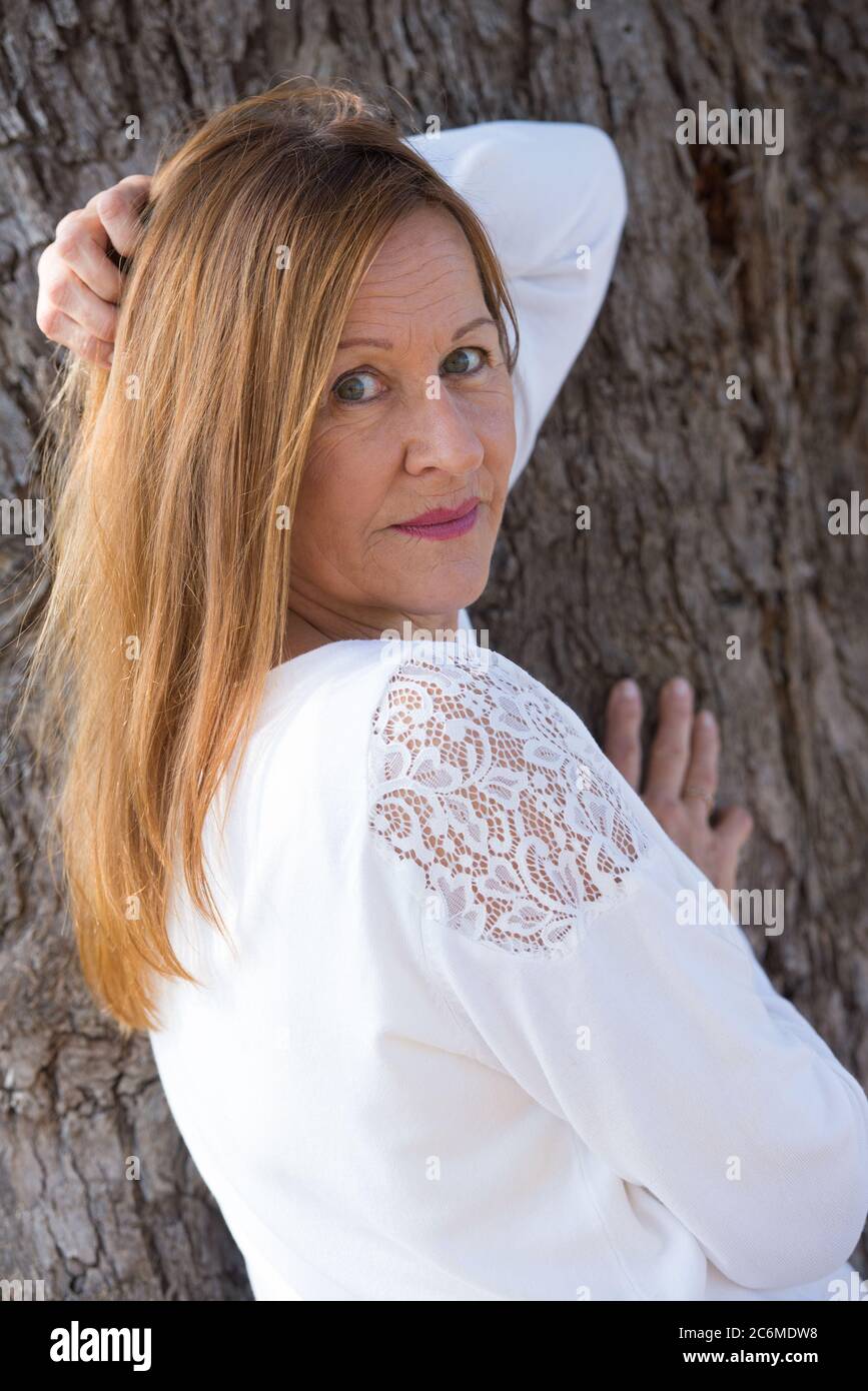 Portrait schöne ältere Frau posiert nachdenklich im Freien, nachdenklich, glücklich freundlich entspannt Lächeln, lange Haare. Stockfoto