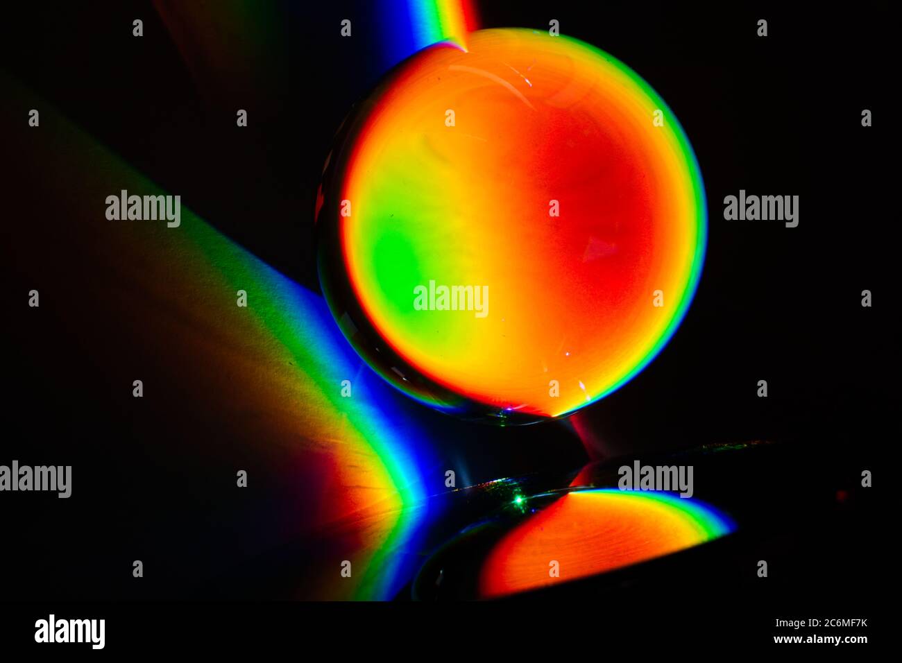 Farben des Regenbogenprodukts des gebrochenen Lichts, das das Spektrum des Lichts zeigt, das von einem sphärischen Glasobjekt Physik und Optik gebogen wird Stockfoto