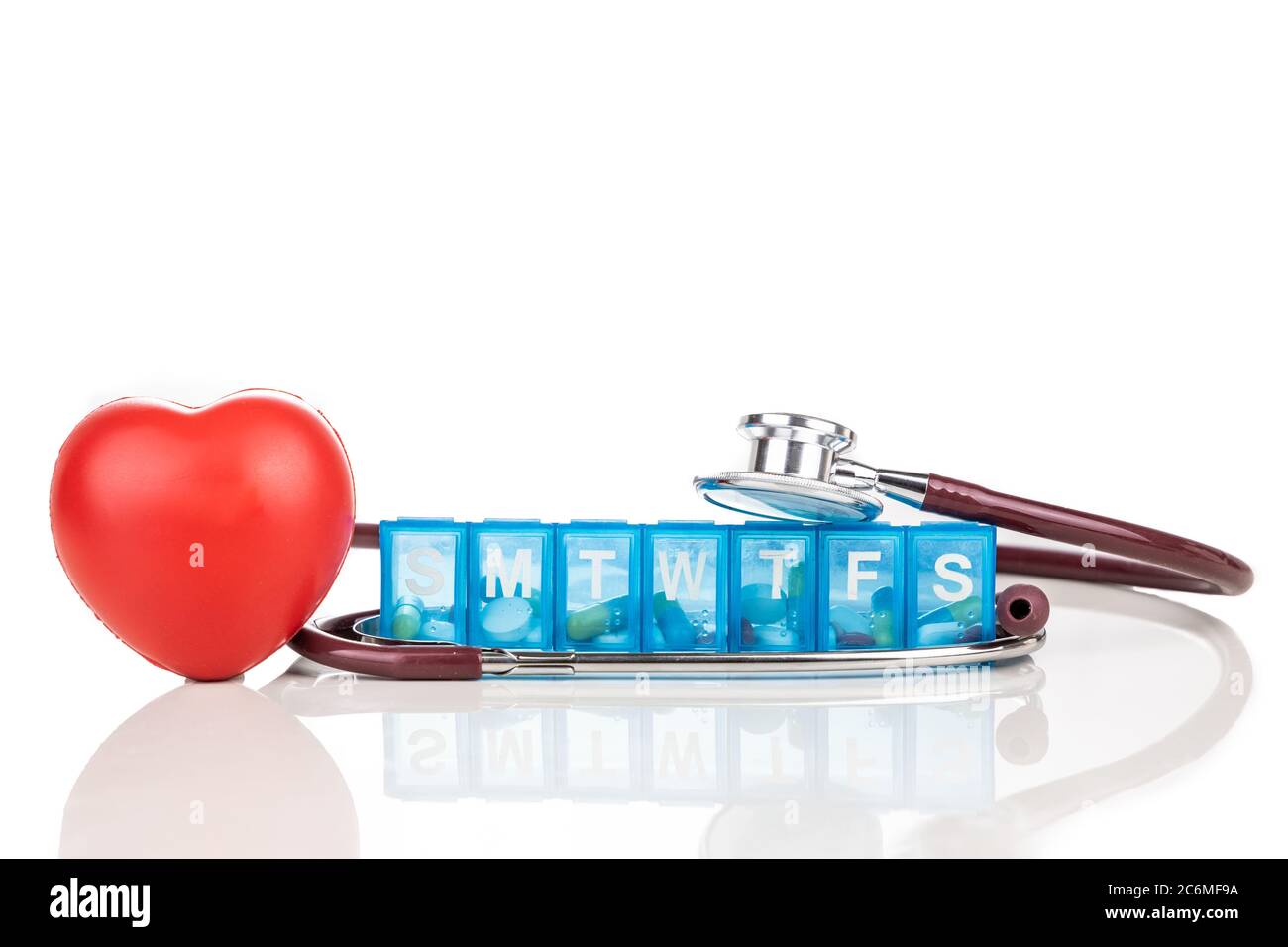 Healthcare-Konzept mit Pille Organizer Box für die Lagerung Dosen der täglichen Medizin, mit rotem Herz und Stethoskop als Requisite auf weißem Hintergrund Stockfoto