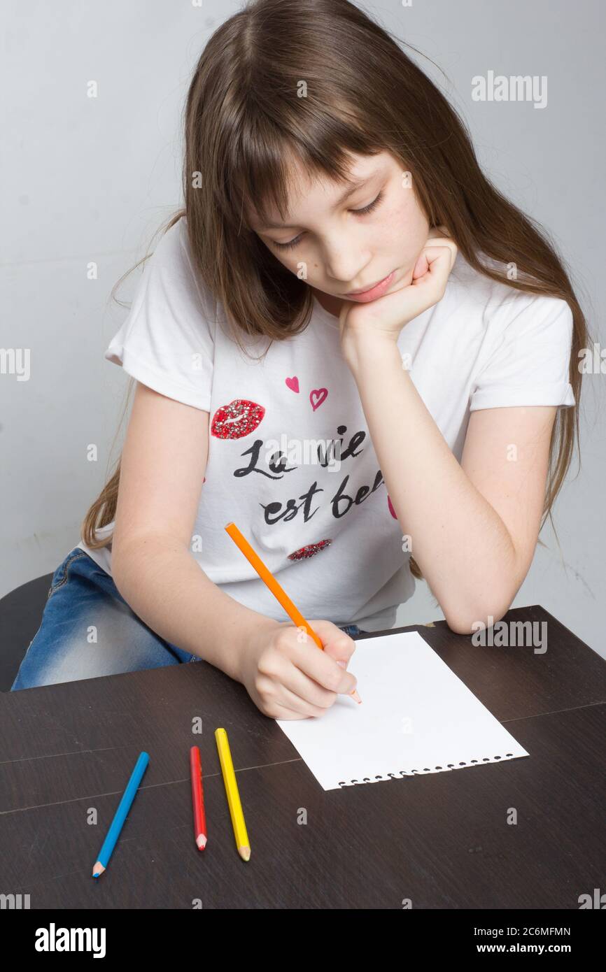 Junge Mädchen Kind sitzt am Tisch, Zeichnung in einem Notizbuch Stockfoto