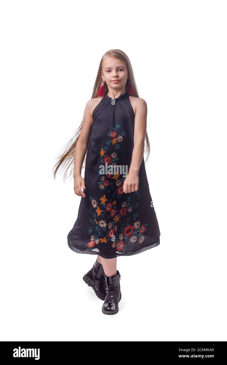 Kind Mädchen mit langen Haaren. In einem schwarzen Kleid mit Blumenmuster auf hellgrauem Studio-Hintergrund. In Sprungbewegung fliegende Haare Stockfoto