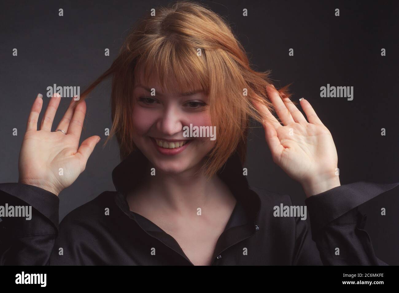 Studio-Portrait einer jungen lustigen Frau mit kurzen Haaren in einer schwarzen Bluse, lachend, zerzaust Stockfoto