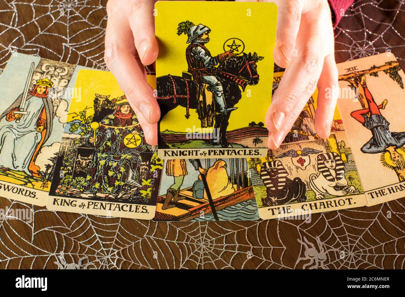 Tarot-Karten aus dem 1910 Rider-Waite Design. Tarot-Lesung mit Ritter und Münzen Karte gehalten. Spider Web Hintergrund. Stockfoto