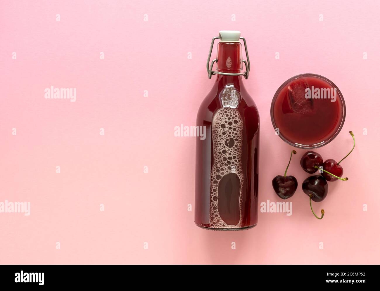 Kalter Kirschsaft in einer Glasflasche mit reifen Beeren Stockfoto