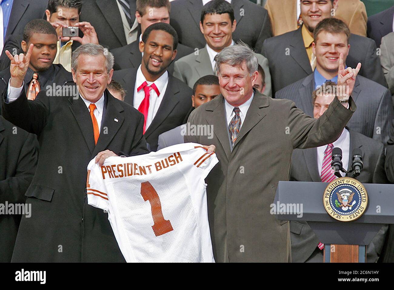 Präsident George W. Bush hält eine Universität von Texas Longhorns Jersey mit Hauptfußballtrainer Mack Braun, wie sie die 'Hook' em Horns geben, Dienstag, Februar 14, 2006 auf dem Südrasen des Weißen Hauses, während der Zeremonien der 2005 NCAA Football Champions zu ehren. Stockfoto