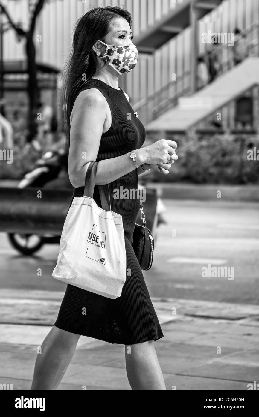 Lady mit Gesichtsmaske und recycelten Einkaufstasche zu Fuß in der Straße während covid 19 Pandemie, Sukhumvit, Bangkok, Thailand Stockfoto