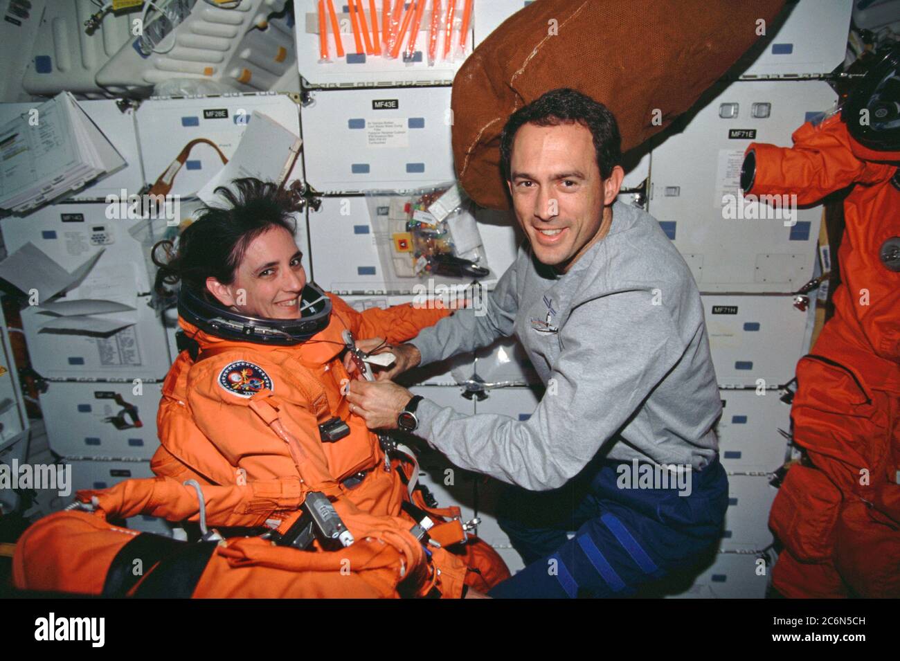 (4-15. Dezember 1998) --- Astronaut James H. Newman unterstützt Astronautin Nancy J. Currie, beide Missionsspezialisten, mit ihrem Starts- und Entry Suit (LES) auf dem Mitteldeck des erdumkreisenden Space Shuttle Endeavour. Die orangefarbenen Anzüge sind Kleidungsstücke in großer Höhe, die von jedem Crew-Mitglied für die Aufstiegs- und Einstiegsphase der Shuttleflüge getragen werden. Stockfoto