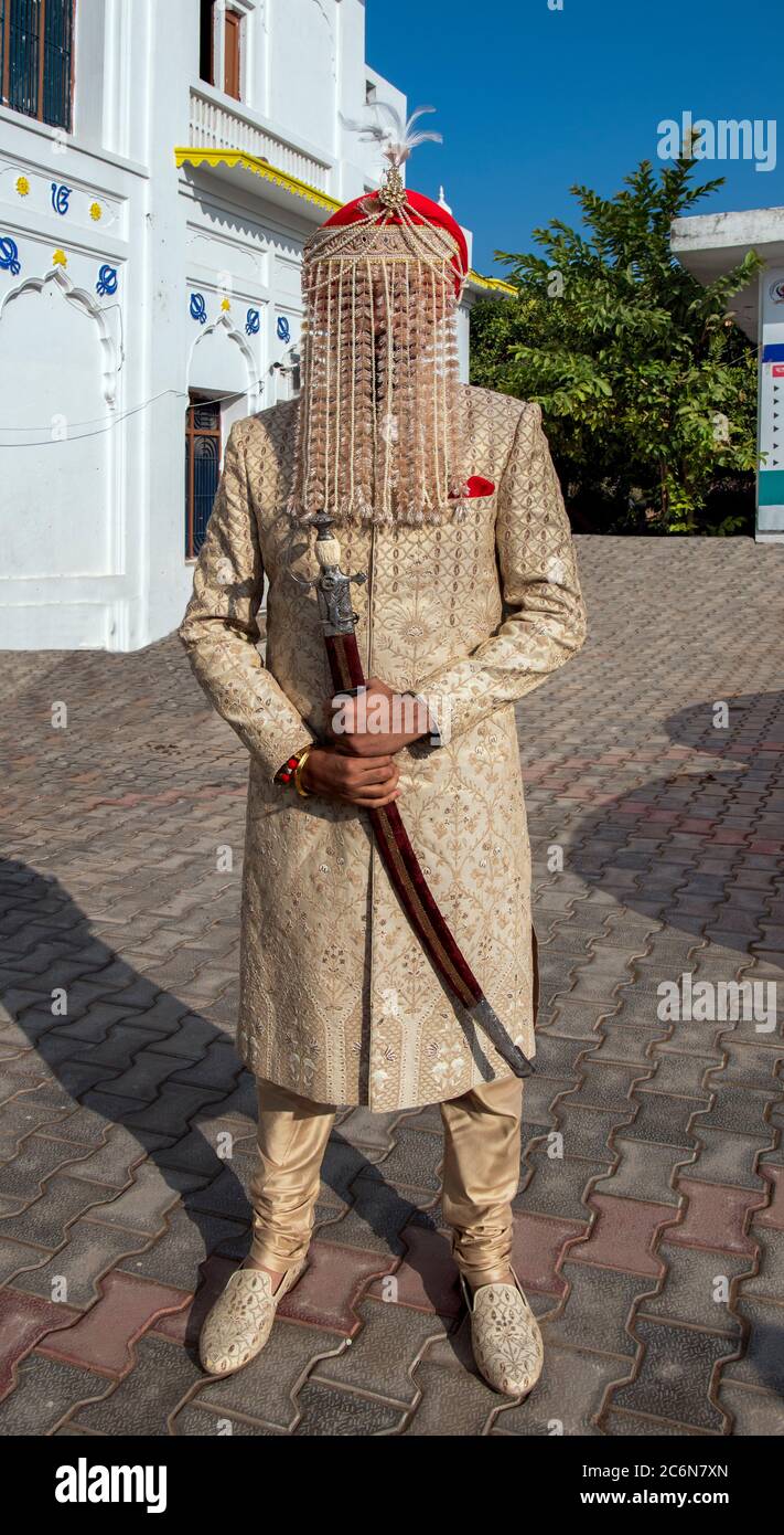 Eleganter Sikh Bräutigam in traditioneller Kleidung inklusive Gesichtsbedeckung pror Zur Trauung und zeremoniellen Schwert Punjab Indien Stockfoto