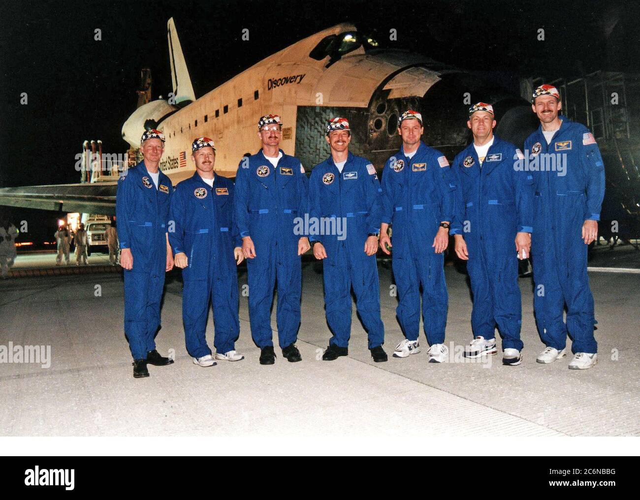 Die STS-82-Crew steht vor dem Space Shuttle Discovery, nachdem sie auf der KSC Shuttle Landing Facility auf der Start- und Landebahn 15 landet, um eine 10-tägige Mission zum Dienst am Hubble Space Telescope (HST) abzuschließen. Crew-Mitglieder sind (von links nach rechts) Mission Specialist Steven A. Hawley, Mission Commander Kenneth D. Bowersox, Mission Specialist Joseph R. 'Joe' Tanner, Pilot Scott J. 'doc' Horowitz, Mission Specialist Gregory J. Harbaugh, Payload Commander Mark C. Lee und Mission Specialist Steven L. Smith. STS-82 ist die neunte nächtliche Landung des Shuttles und die vierte nächtliche Landung am KSC. Stockfoto