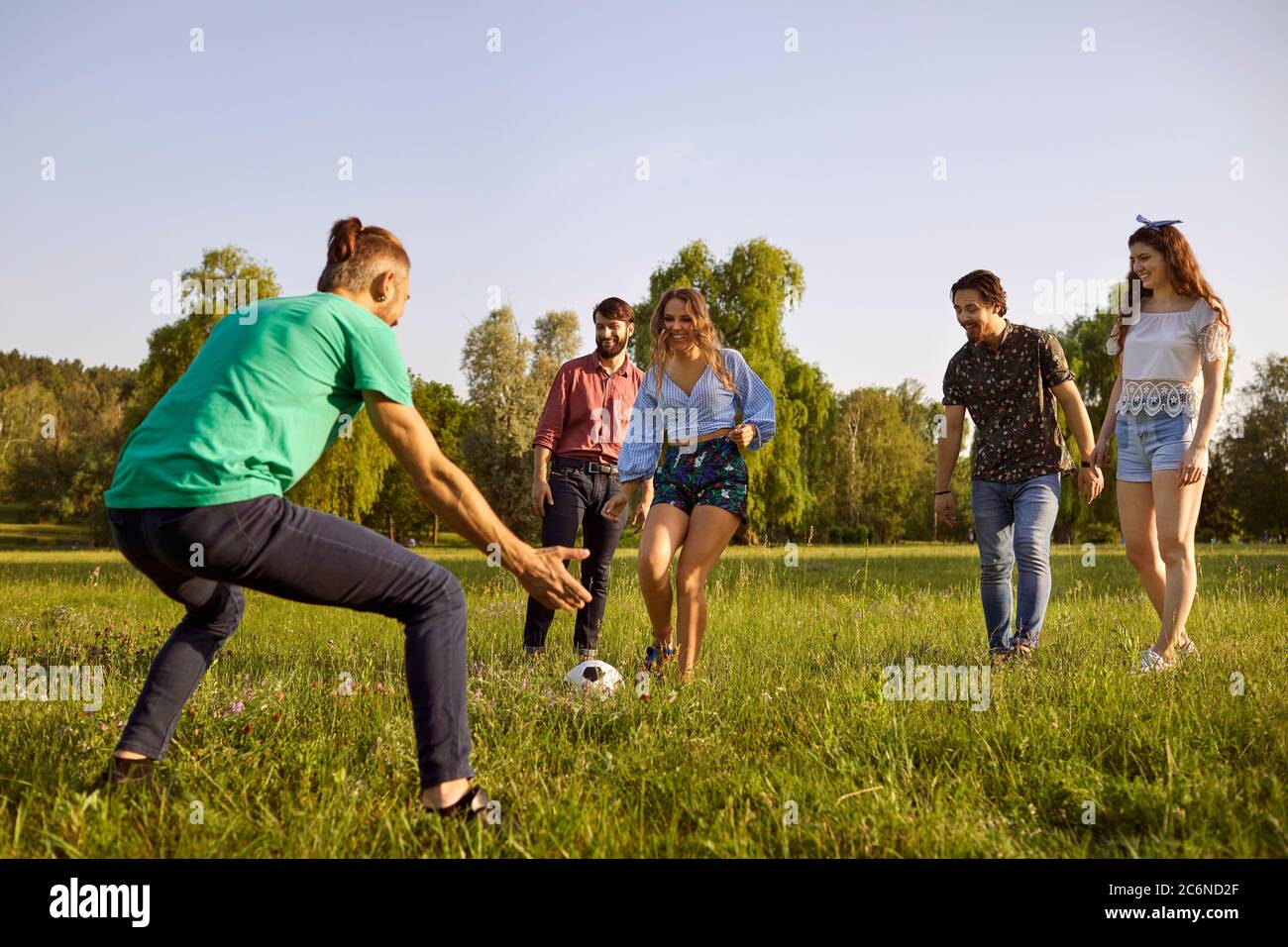 Gesellschaft von Freunden, die Fußball auf der Wiese spielen Stockfoto