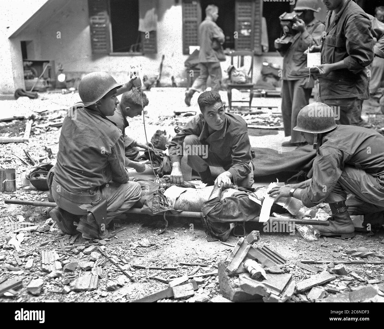 Sanitäter, die der 37. Infanterie-Division zugewiesen wurden, geben Plasma an einen Soldaten, der während der Schlacht in der ummauerten Stadt Intramuros, einem spanischen Fort aus dem 16. Jahrhundert, am 25. Februar 1945 in Manila, Philippinen, verwundet wurde Stockfoto