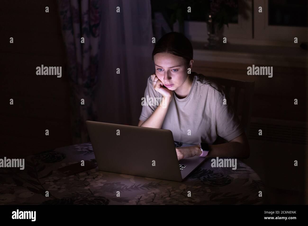Freiberufliche Mitarbeiterin, die spät abends zu Hause am Laptop arbeitet und soziale Medien teilt. Distanzauftrag Stockfoto