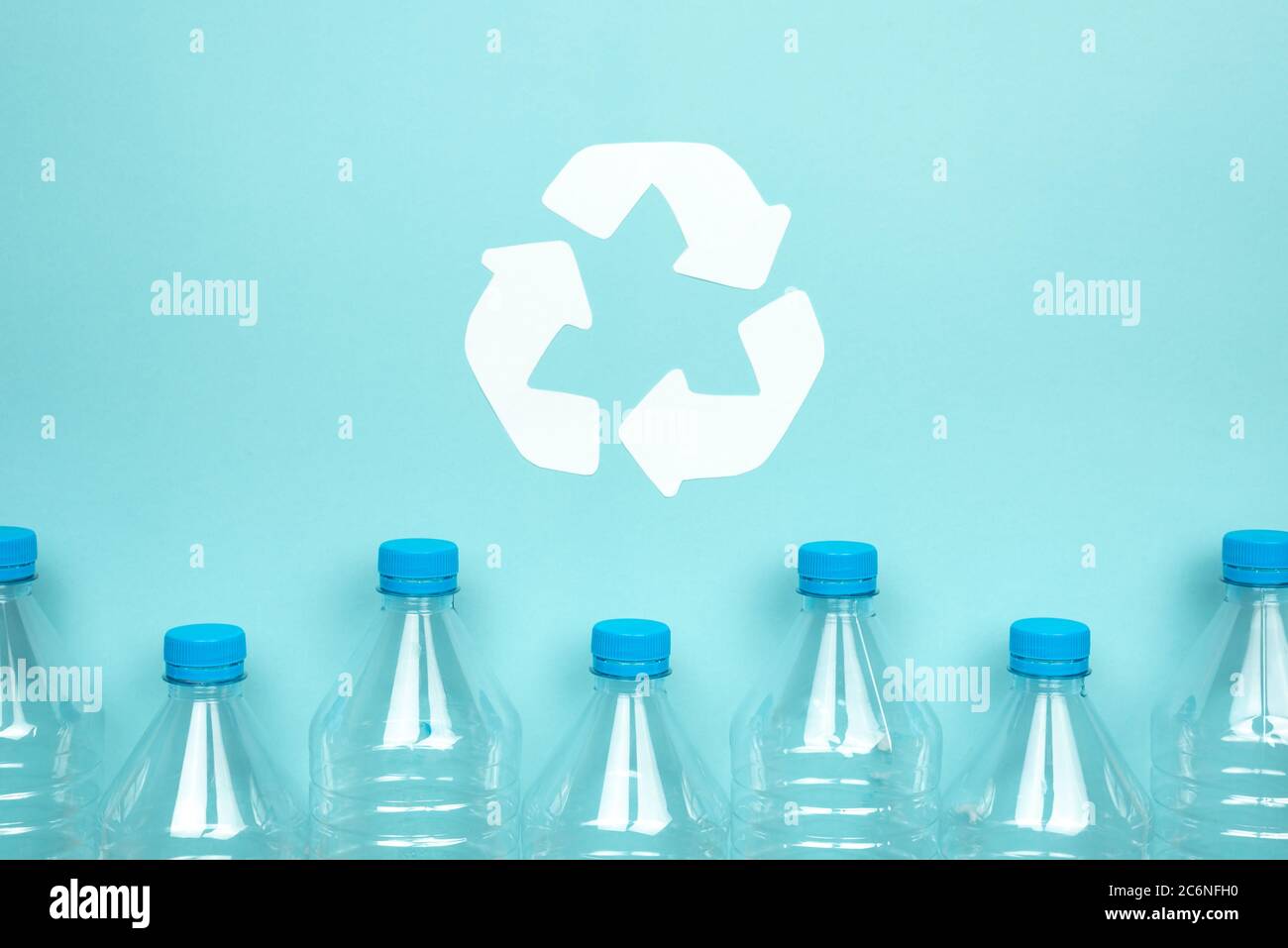Horizontales Farbbild mit einer Vorderansicht einer durchsichtigen Plastikflasche mit Verschlüssen auf blauem Hintergrund. Recycling- und Umweltkonzept. Stockfoto