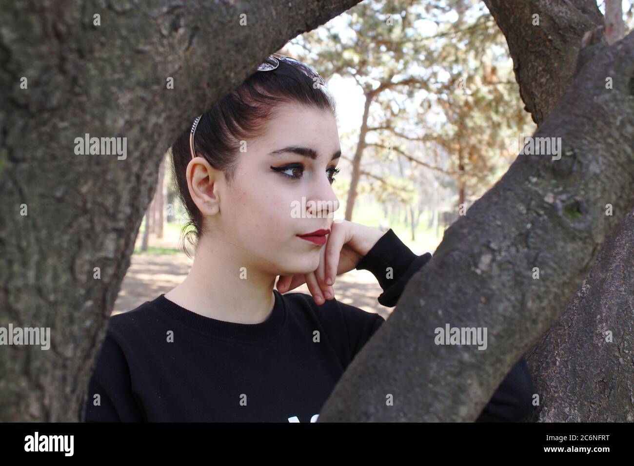 Porträt eines jungen Mädchens hinter einem Baum draußen Stockfoto