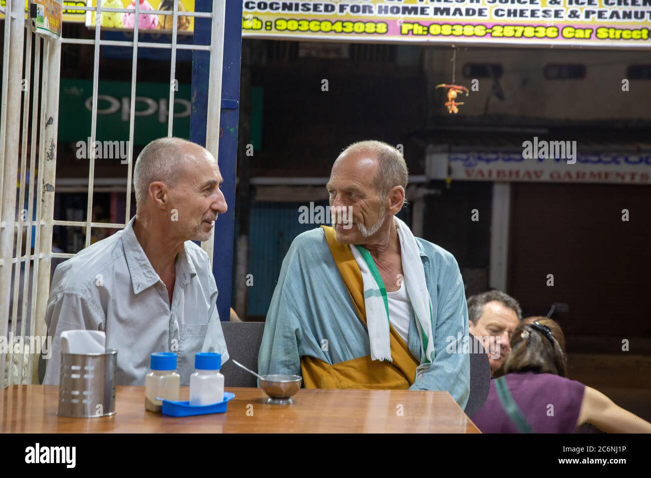 02/19/2019 Gokarna , Indien. Zwei Menschen mit europäischem Auftritt sprechen miteinander und lächeln in einem Café für den Abend. südindien. Stockfoto